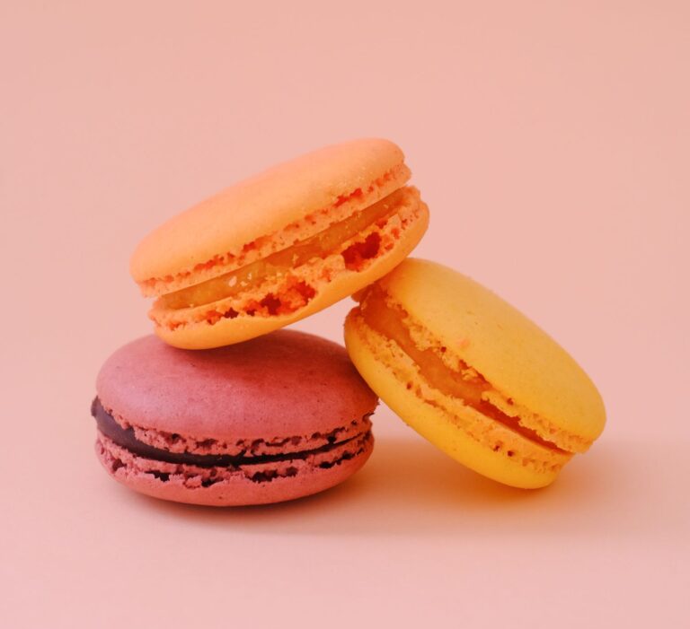 Three vibrant macarons against a pink backdrop, capturing elegance and sweetness.
