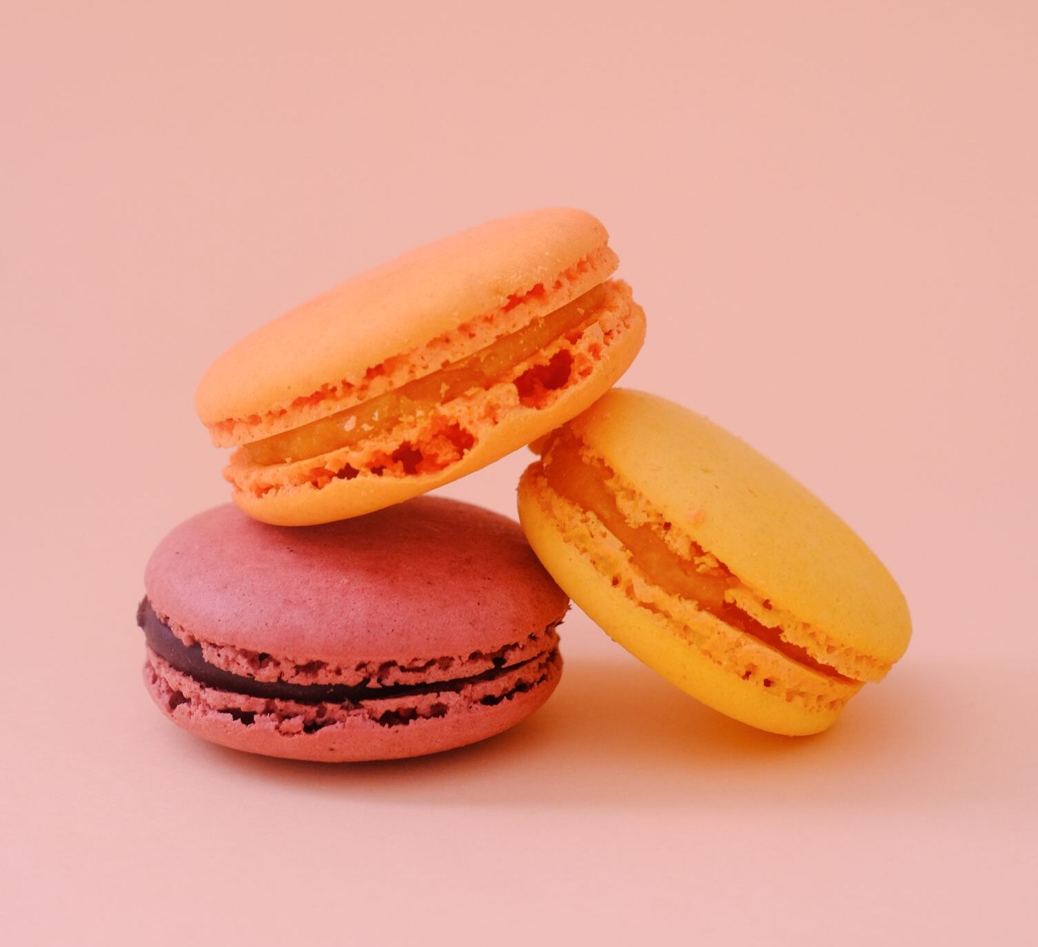 Three vibrant macarons against a pink backdrop, capturing elegance and sweetness.